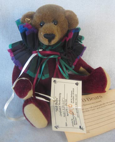 Small bear with brown head, maroon body, and colorful ruff