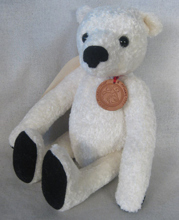 White teddy bear with textured fur, black felt nose and paw pads