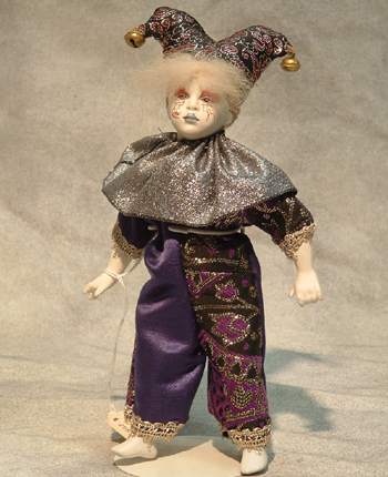Part of the Uta Brauser's Renaissance Figurines, this small boy is dressed in a purple and silver brocade outfit and jester's hat. $295.00
